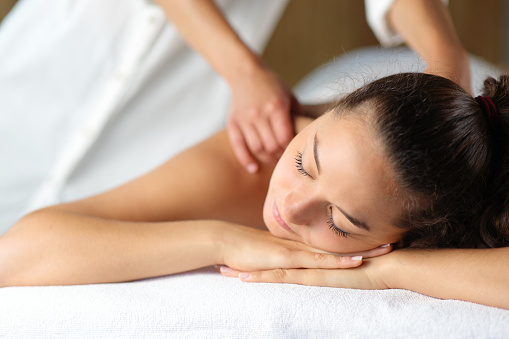 Woman relaxing with therapist massaging in spa